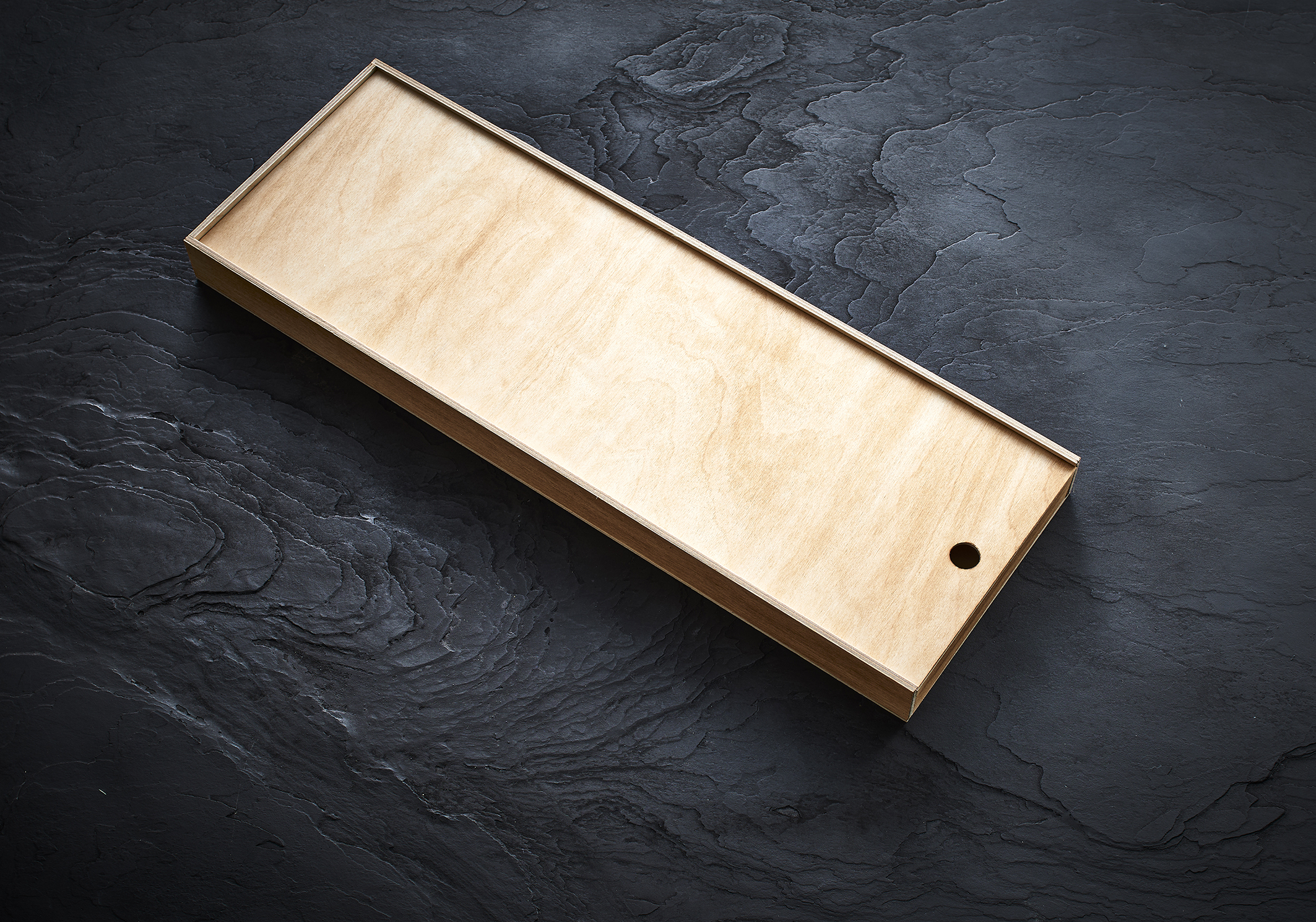 Unbearbeitete Holzkiste mit minimalistischem Design, ideal zur Aufbewahrung und Organisation, vor einem dunklen, strukturierten Hintergrund. – Fishing Adventure GmbH